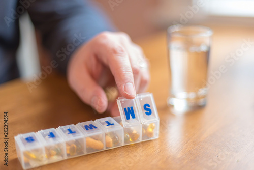 Man using a pill holder to organize daily vitamins and supplements