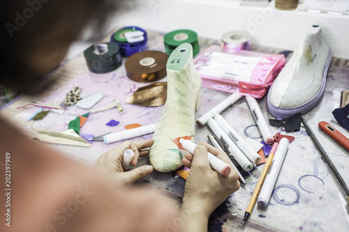 Woman designer making handmade shoes in her workshop