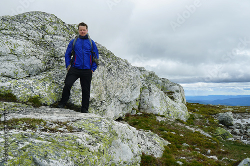 Young male tourist standing on the rock background.