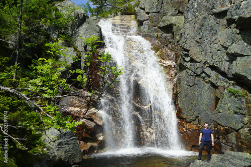 A man standing near waterfall.