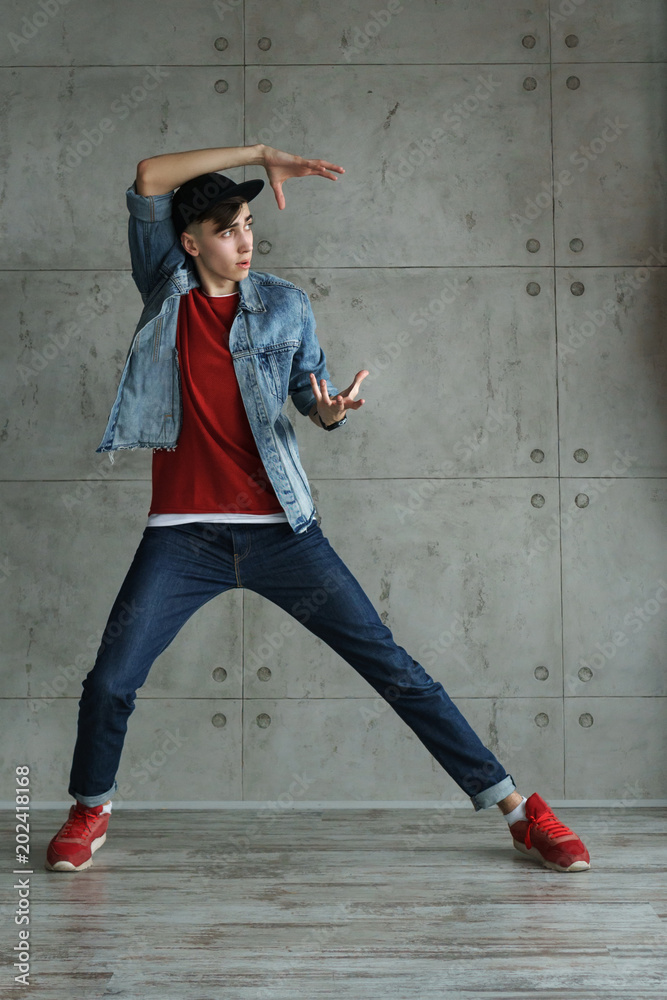 Teenage boy in jeans and red sweater, denim jacket and baseball cap dancing  hip-hop. Dynamics of modern dance movement Stock Photo | Adobe Stock