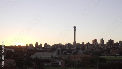 JOHANNESBURG, SOUTH AFRICA, 24 APRIL 2018 - Timelapse of the sun rising over Hillbrow with Hillbrow tower, Ponte City, BDO building, and Parktown Boys sports fields visible. photo