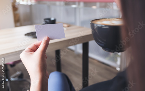 A woman holding an empty business card while drinking coffee cup