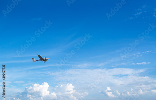 Plane flies in the blue sky against the background of clouds