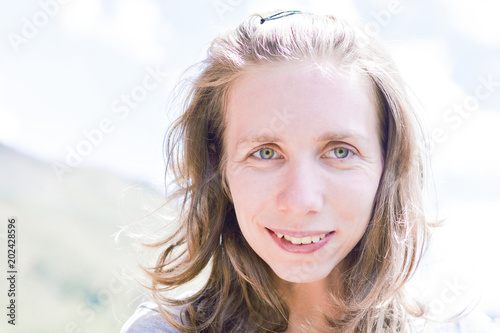 Young caucasian woman smiling outside.
