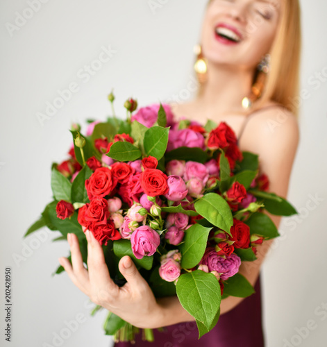 Fototapeta Naklejka Na Ścianę i Meble -  Beautiful woman hold bouquet of red and pink roses flowers happy smiling on grey 