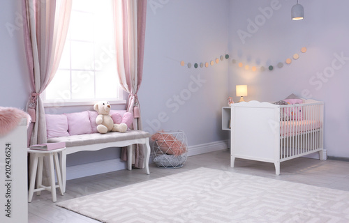 Baby room interior with comfortable crib and indoor bench