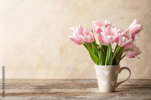 Fototapeta Naklejka Na Ścianę i Meble -  Cup with beautiful tulips for Mother's Day on table