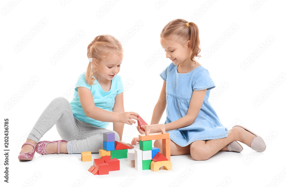Cute little girls playing with building blocks on white background Cute little girls playing with building blocks on white background