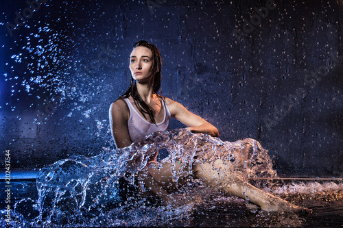 Girl with long hair during photoshoot with water in photo studio