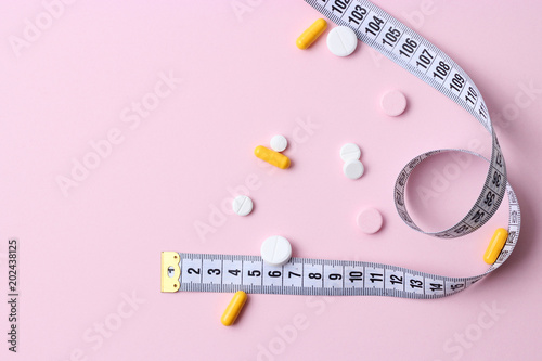  centimeter tape and pills on a pastel background with space for text. concept diet, burn fat and calories, weight loss. Bioadditives.