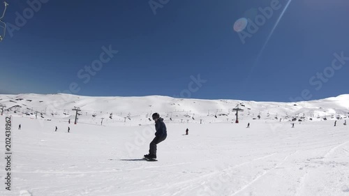 4K. A snowboard rider is sitting in the snow, he getting up and sliding down the snowy slope. There are chairlifts and cable cars. Sierra Nevada, Spain-Adrian.