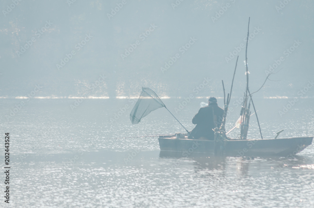 Fisherman in a wooden boat on the lake 