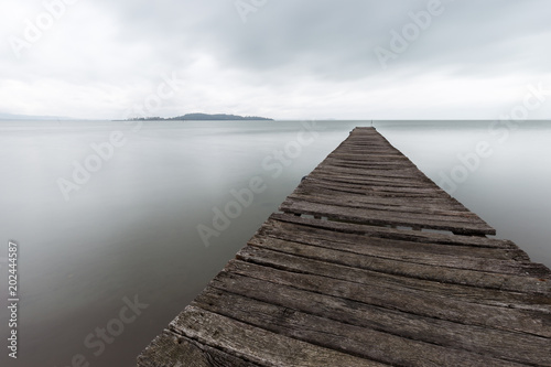 Long exposure first person view of a pier on a lake with perfectly still water