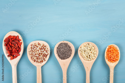 Various superfoods goji berries, quinoa, chia, hemp seeds and lantils on blue background. Vegan, vegetarian and healthy eating diet and organic products concept