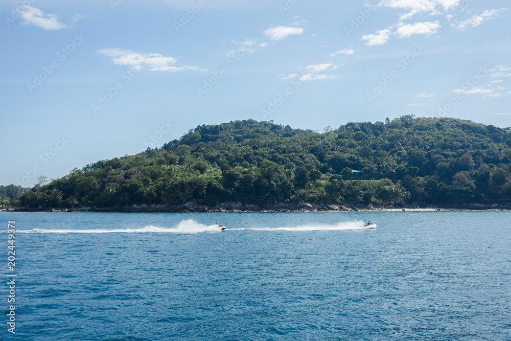 both  jet ski riding past Phuket island coast