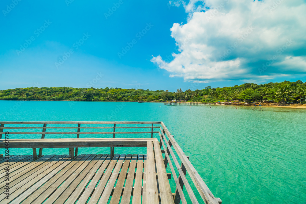 Fototapeta premium Wooden pier or bridge with tropical beach and sea in paradise island