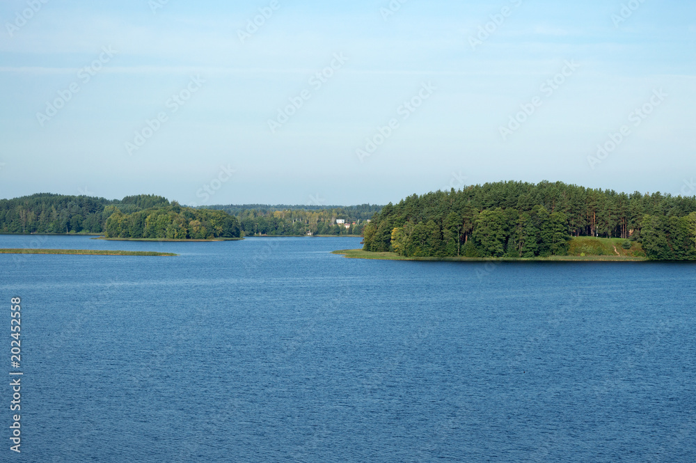 Breathtaking scenery of blue waters of Zarasas lake with forest and houses on the horizon, Zarasai, Lithuania. Beautiful lake landscape on summer sunny day