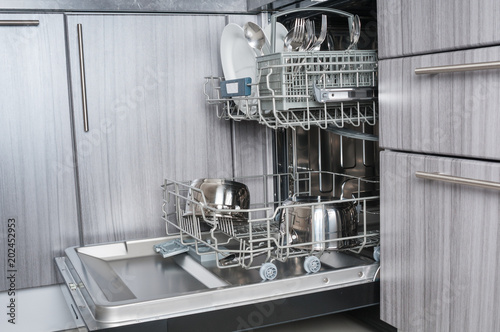 Open dishwasher machine with clean utensils close up