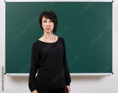 girl teacher posing by chalk Board, learning concept, green background, Studio shot