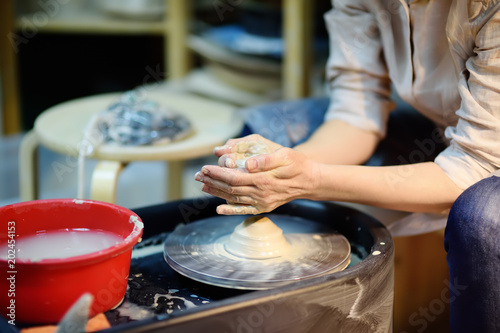 Close-up photo of hands of woman making clay object