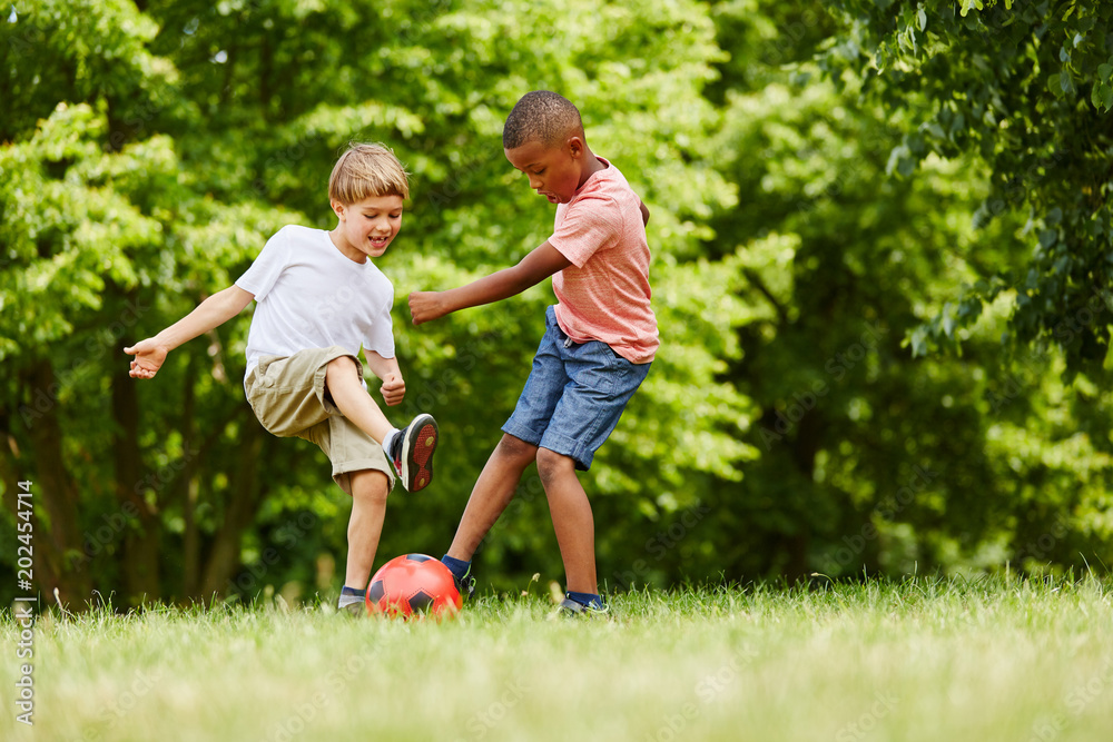 Zwei Kinder spielen Fußball im Sommer