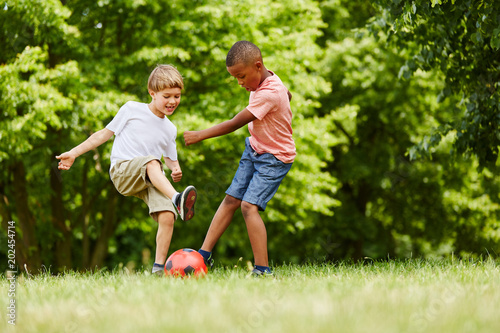 Zwei Kinder spielen Fußball im Sommer