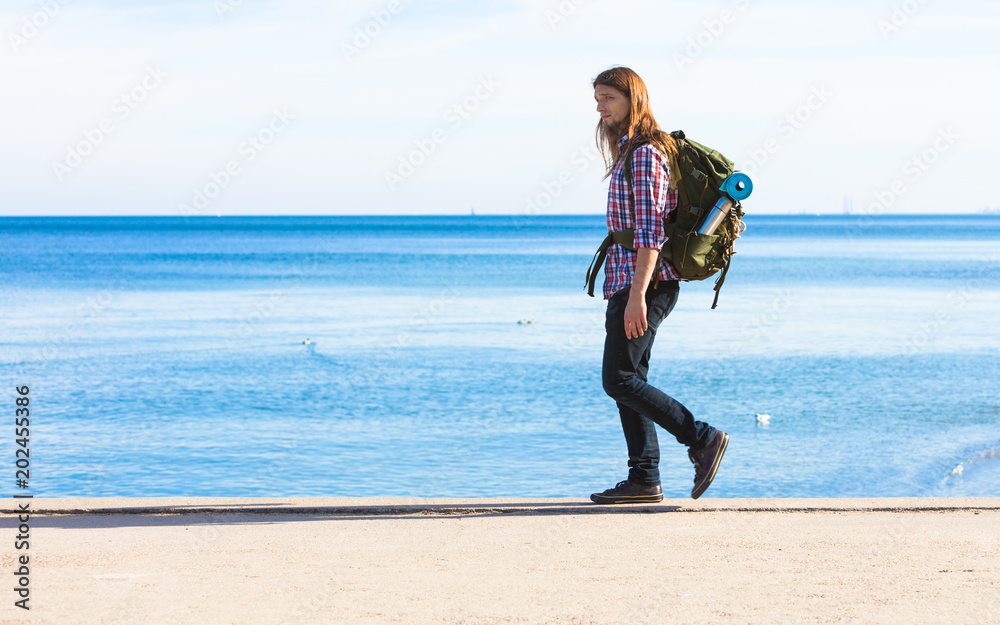 Fotografie Man hiker with backpack tramping by seaside