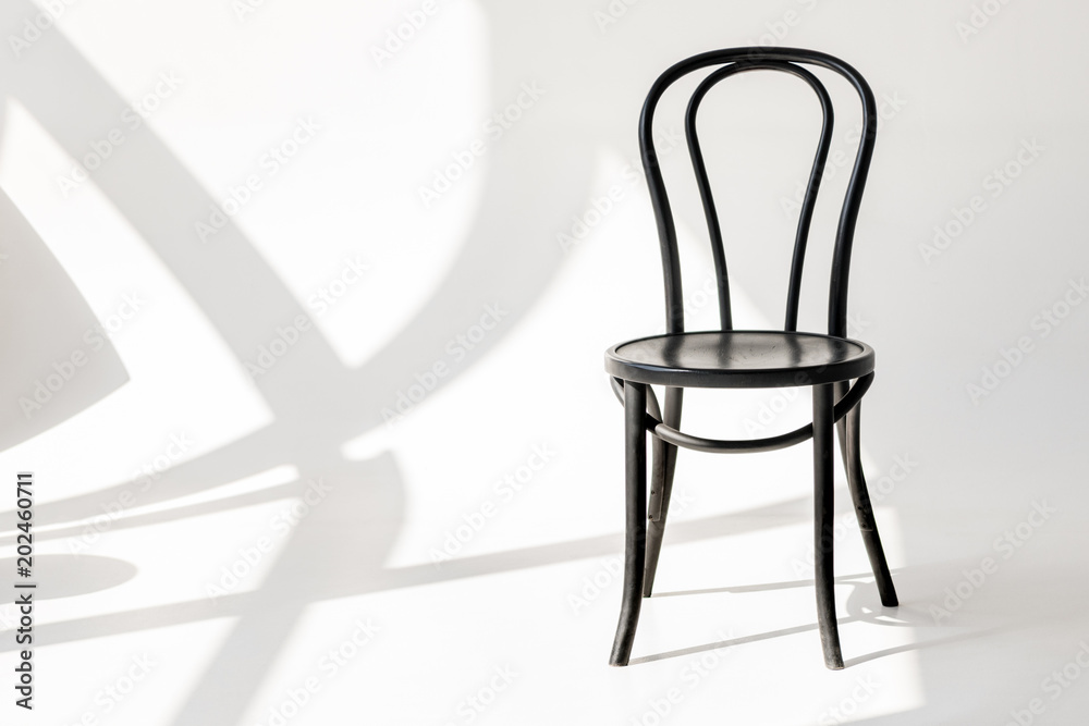 close up view of black wooden chair on grey backdrop with shadows close up view of black wooden chair on grey backdrop with shadows