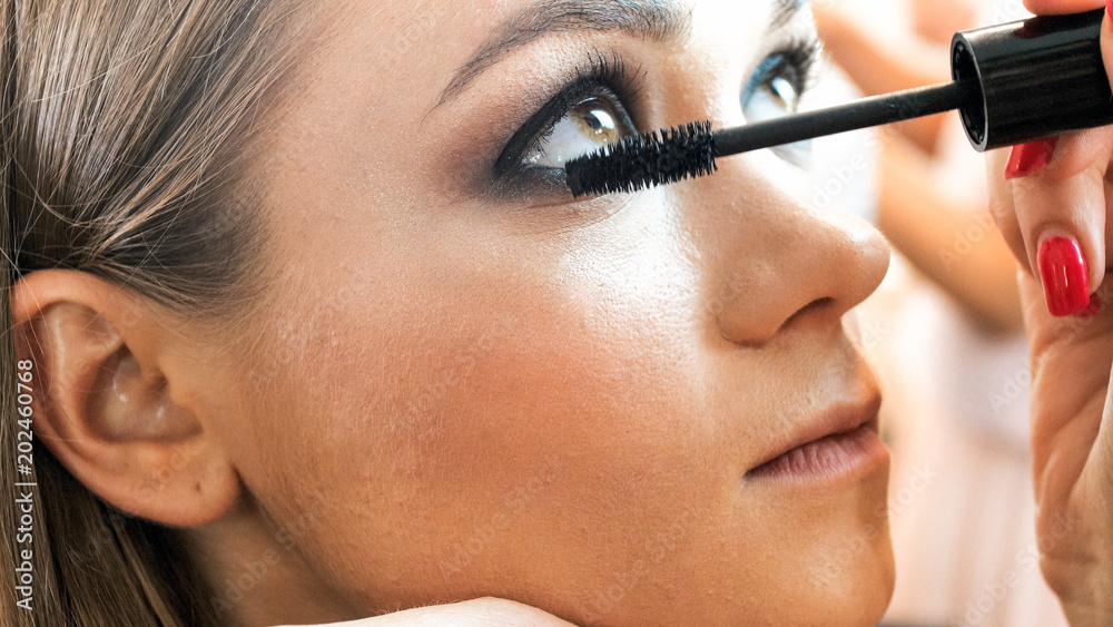 Closeup image of makeup artist applying mascara on eyelashes
