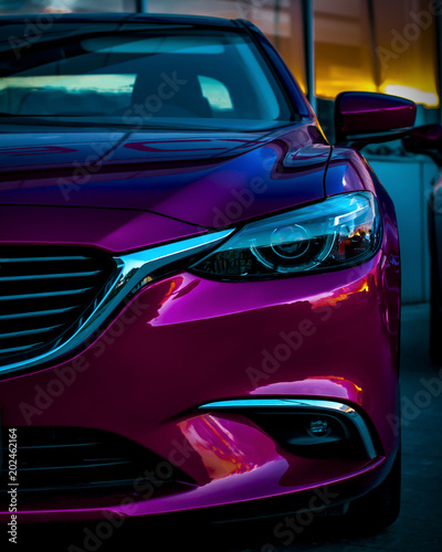 Close up shot of headlight in luxury violet car background. Modern and expensive sport car concept