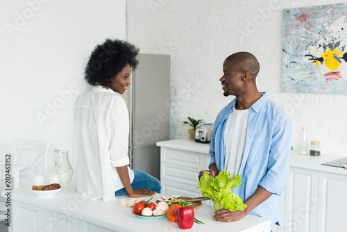 african american couple with fresh vegetables on table in morning at home