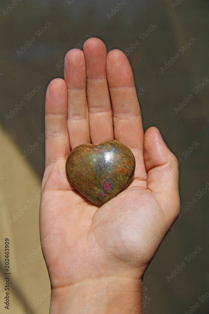 Φωτογραφία The hand holds the heart from the natural stone of the iotsit