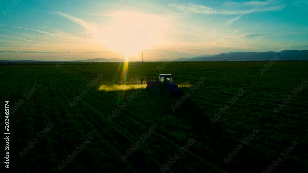 Aerial view of farming tractor plowing and spraying on field Aerial view of farming tractor plowing and spraying on field