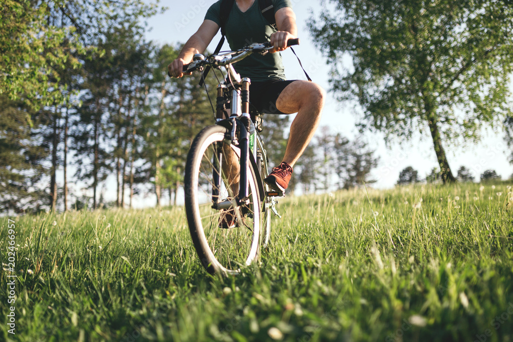 Fototapeta premium Cyclist man feet riding mountain bike on outdoor trail deep grass