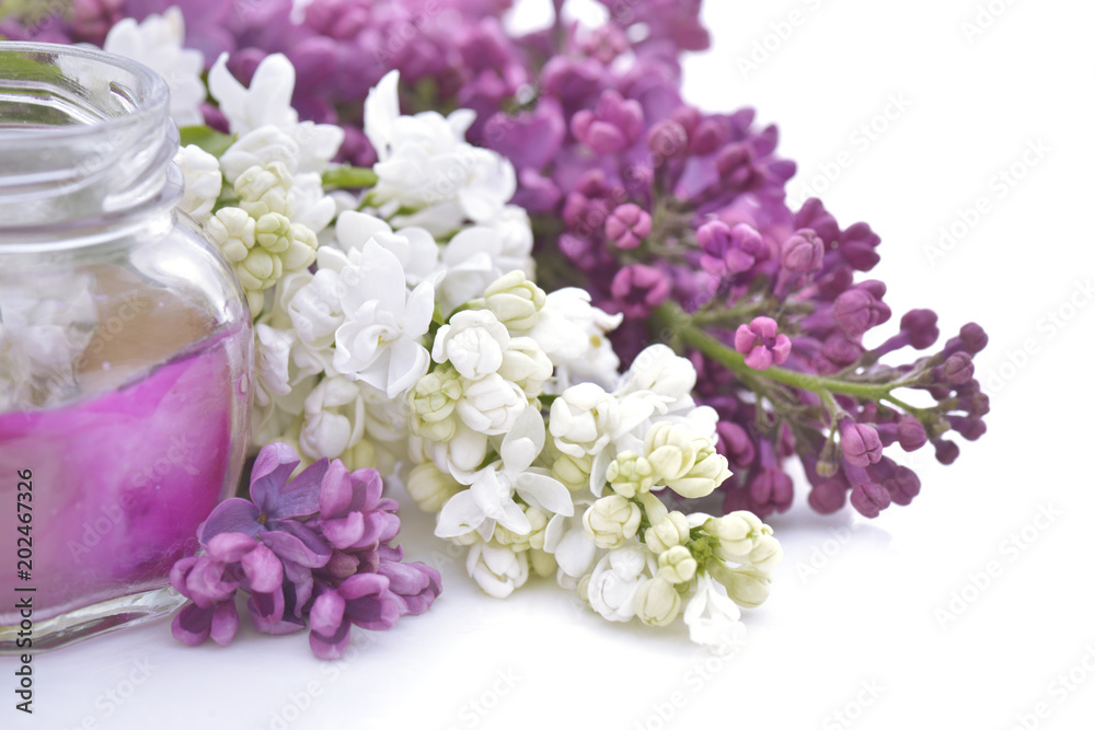 Glass candle among flowers of pink and white lilac on white background Glass candle among flowers of pink and white lilac on white background