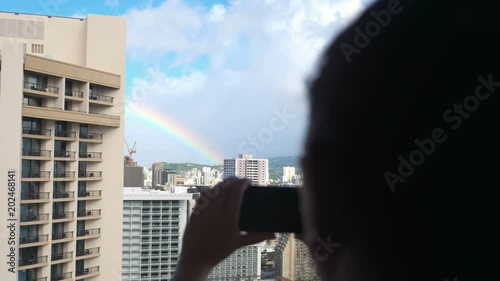  Professional video of woman taking picture of rainbow above Honolulu in 4K slow motion 60fps photo