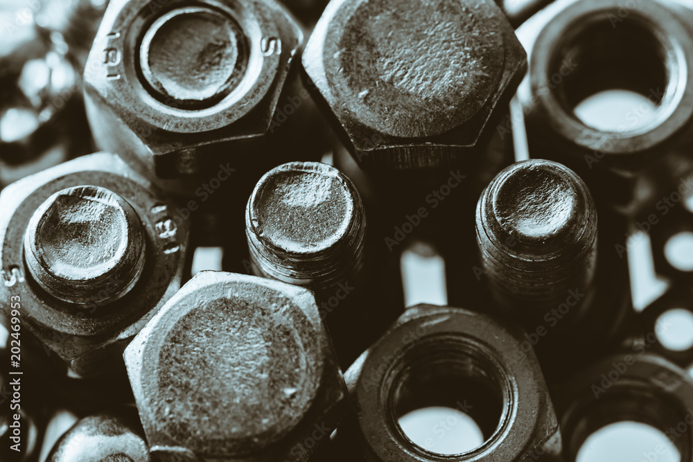 Art monochrome background of bolts and nuts close up in backlight. Small fasteners in macro. Art monochrome background of bolts and nuts close up in backlight. Small fasteners in macro.