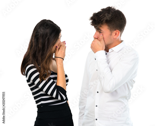 Young couple covering mouth with hands on isolated white background