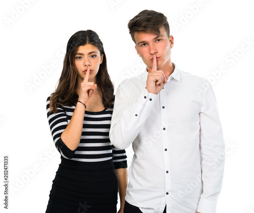 Young couple showing a sign of closing mouth and silence gesture on isolated white background