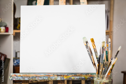 Art equipment: easel, brushes, tubes with paint, palette and paintings