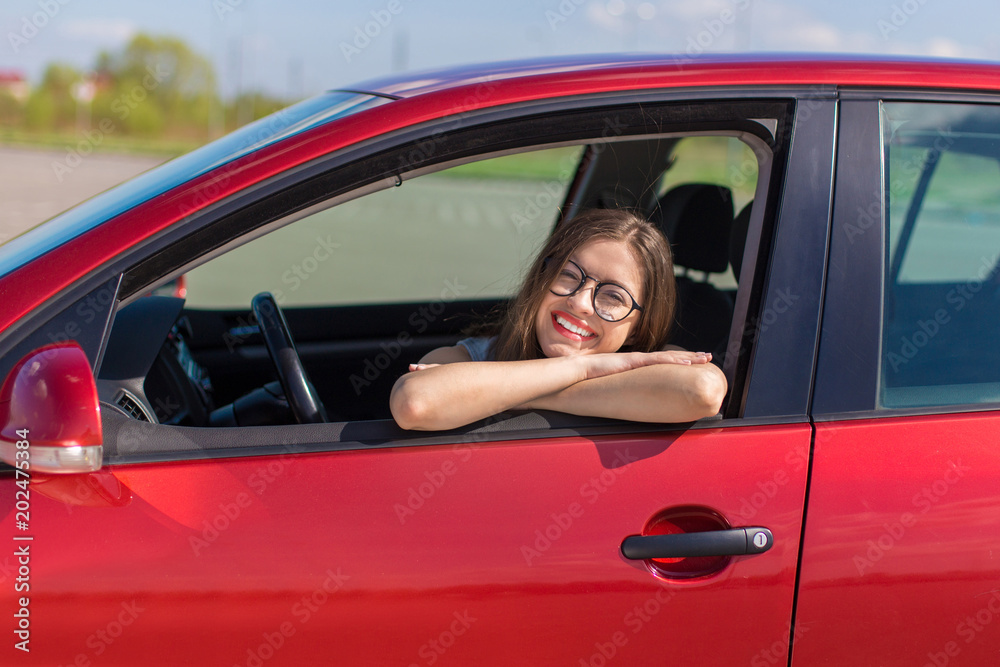 Young woman in car. Girl driving a car. Smiling young woman sitting in red car
Young woman in car. Girl driving a car. Smiling young woman sitting in red car