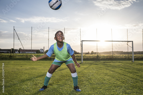 Young football player heading the ball on football ground
