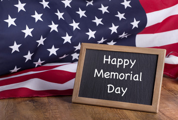 Happy Memorial Day text on a blackboard with the American flag in background