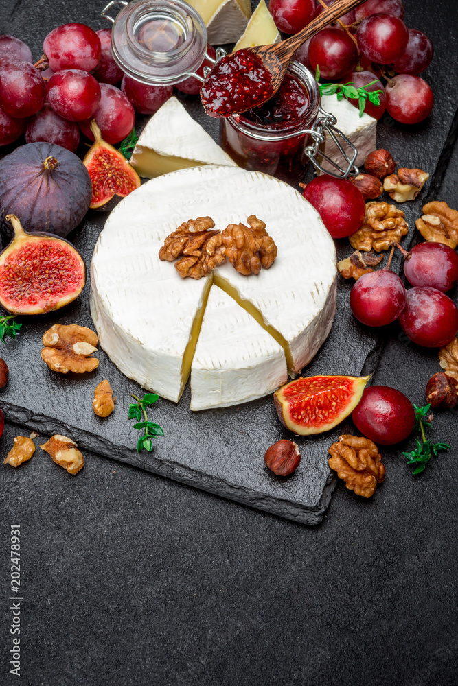 Camembert cheese and walnuts on stone serving board