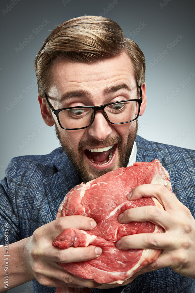 A man in a business suit with a piece of raw meat. A man in a business suit with a piece of raw meat.