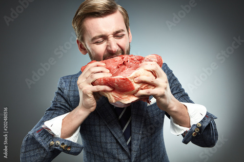 A man in a business suit with a piece of raw meat.