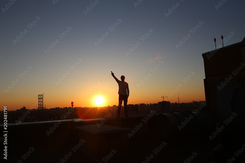 silhouette  man raised  hand up roof  building sunset