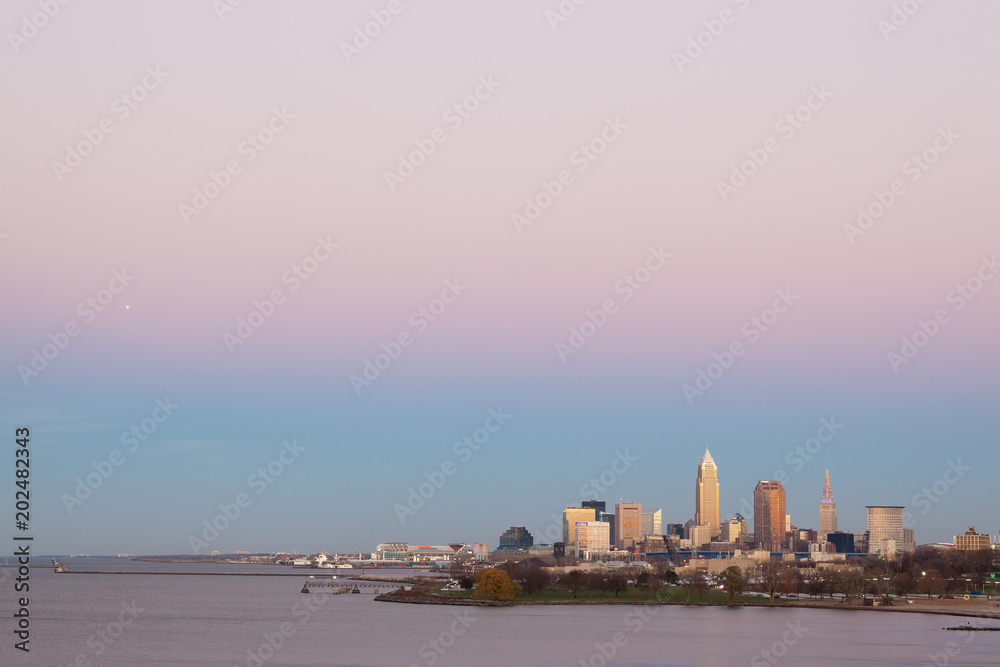 The Cleveland skyline with a pink sky on the coast of Lake Erie for sunset.