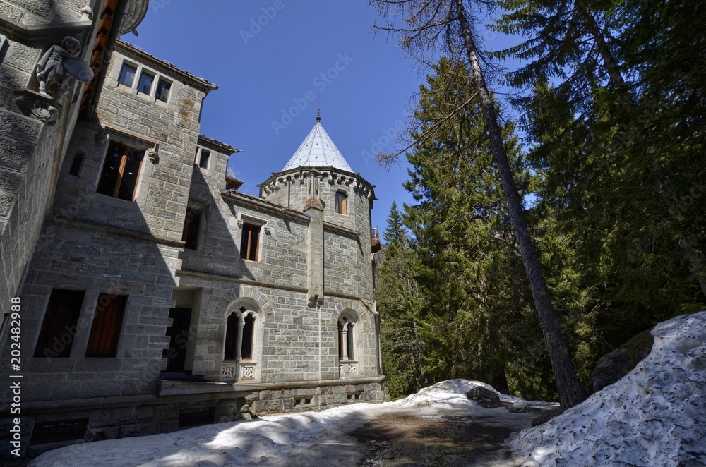 Gressoney-Saint-Jean, Valle d'Aosta region, Italy. 25 April 2018. Castel Savoia, is a villa built in the late 1800s in eclectic style. In a fairytale context, photos of the exterior. Sunny day. Gressoney-Saint-Jean, Valle d'Aosta region, Italy. 25 April 2018. Castel Savoia, is a villa built in the late 1800s in eclectic style. In a fairytale context, photos of the exterior. Sunny day.